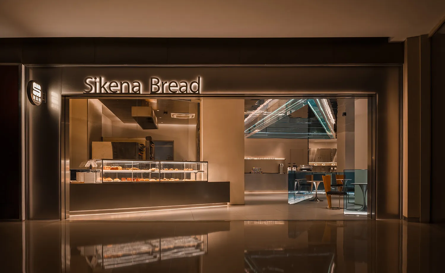 A bakery storefront with warm, modern lighting displaying baked goods inside a glass case.