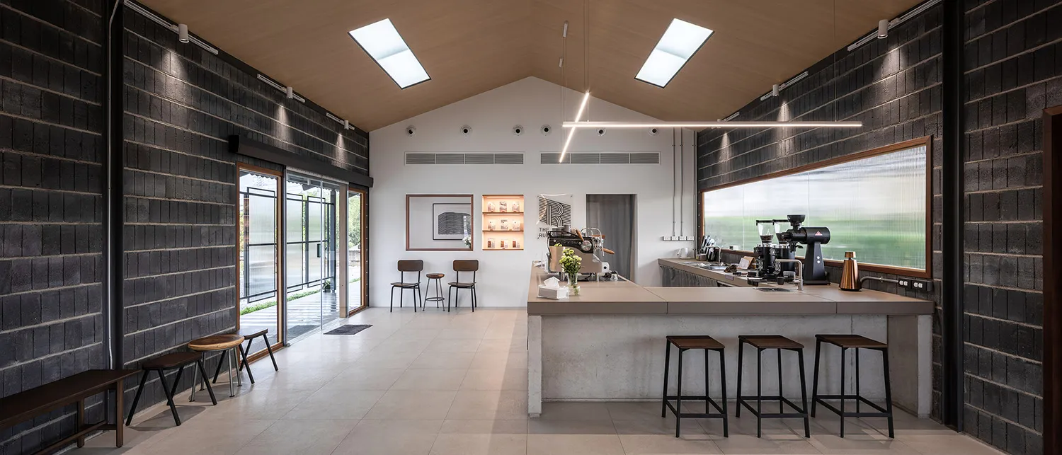 Minimalist coffee shop interior with concrete counter and stools, featuring industrial-style design elements.