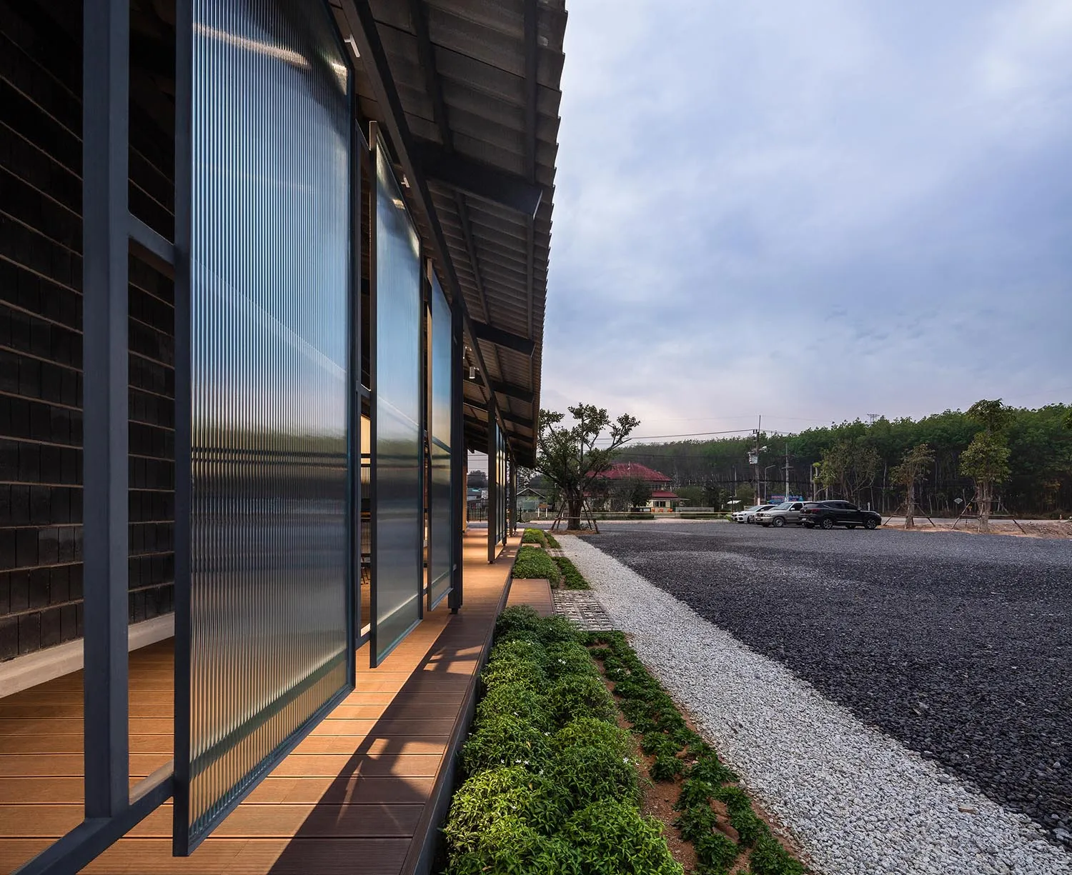 Modern building with metallic panels and wooden walkway.