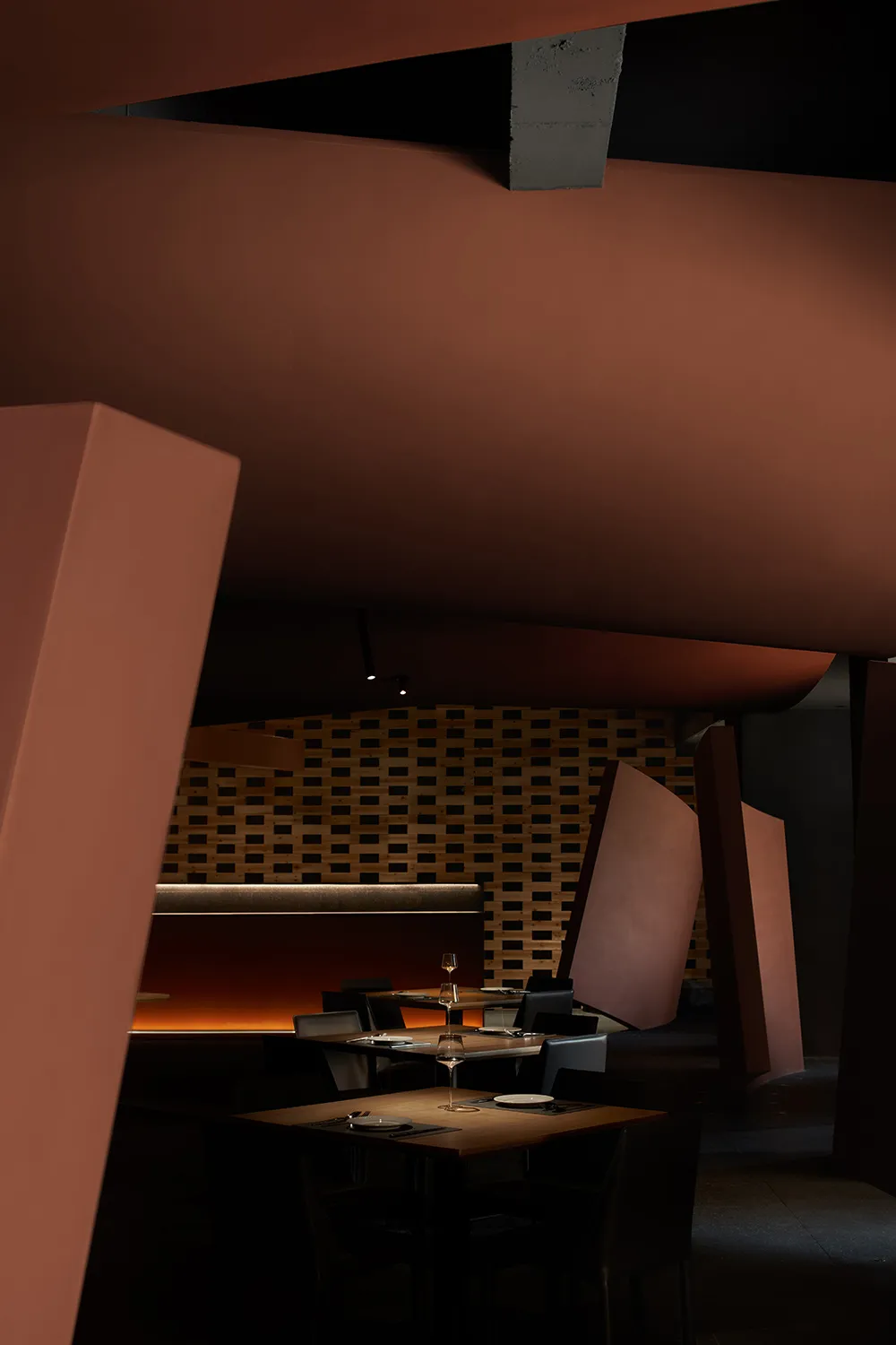 Modern industrial styled restaurant interior with concrete walls, leather chairs, and wood tables.