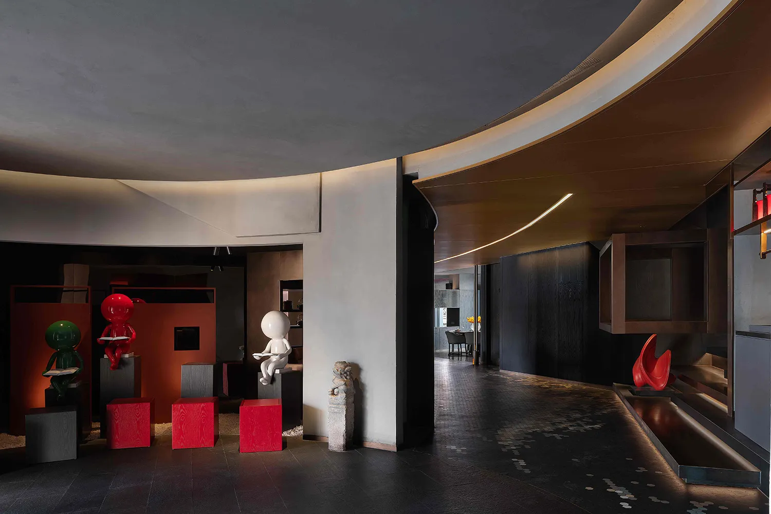 Modern lobby with concrete walls, black tiles, and red stools.