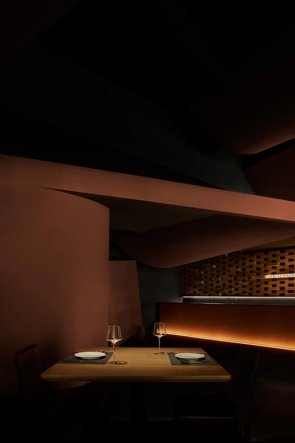 Modern restaurant interior with dark wooden walls, glass elements, and ambient lighting