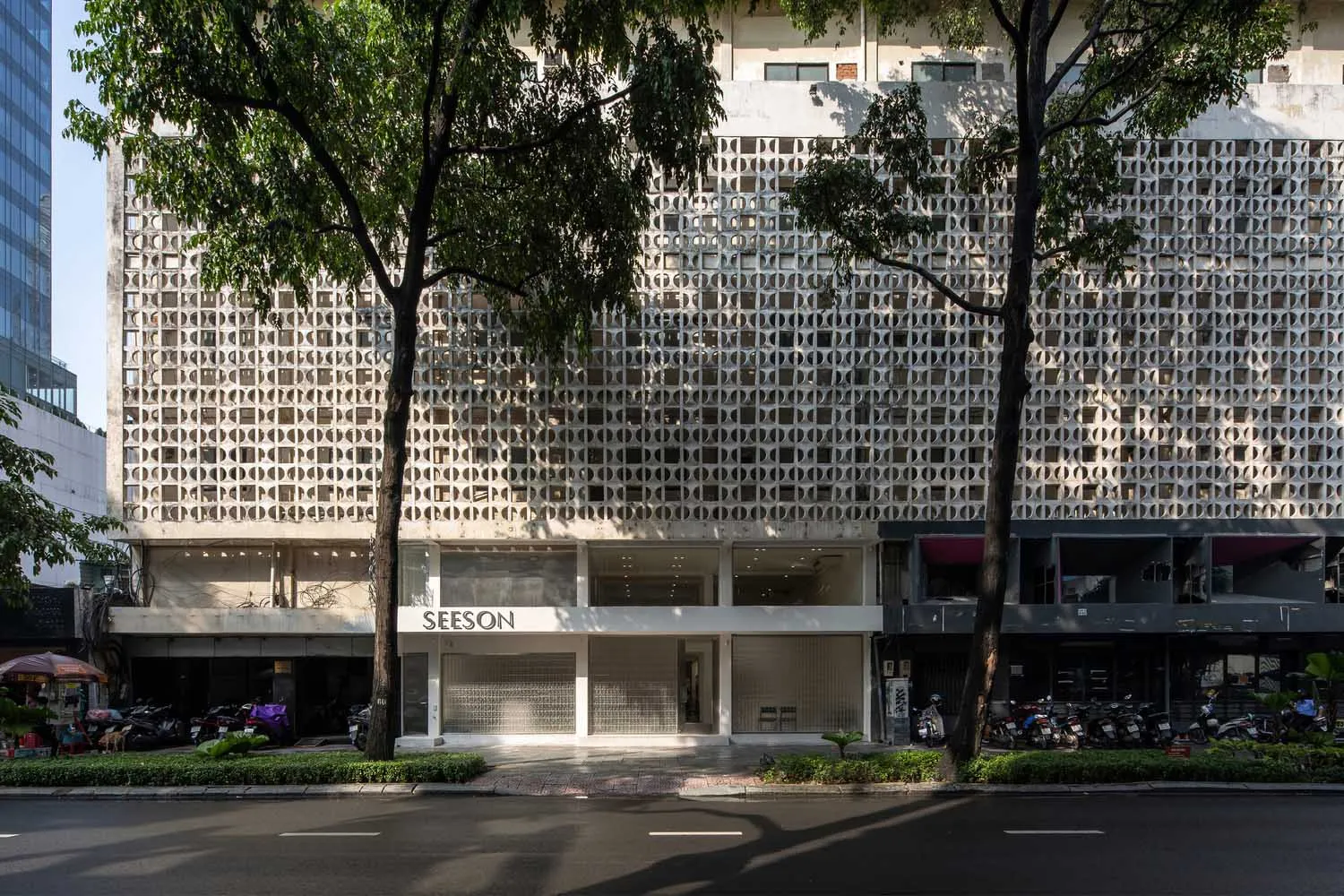 A concrete facade of an office building, featuring a repetitive geometric pattern and large windows.