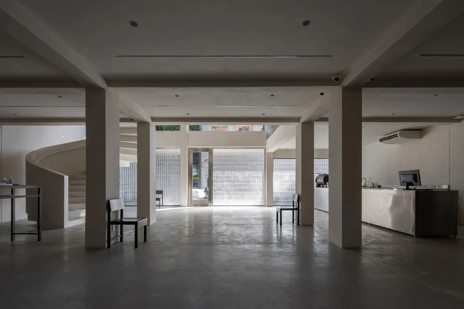 A minimalist coffee shop interior with concrete flooring and glass block walls.