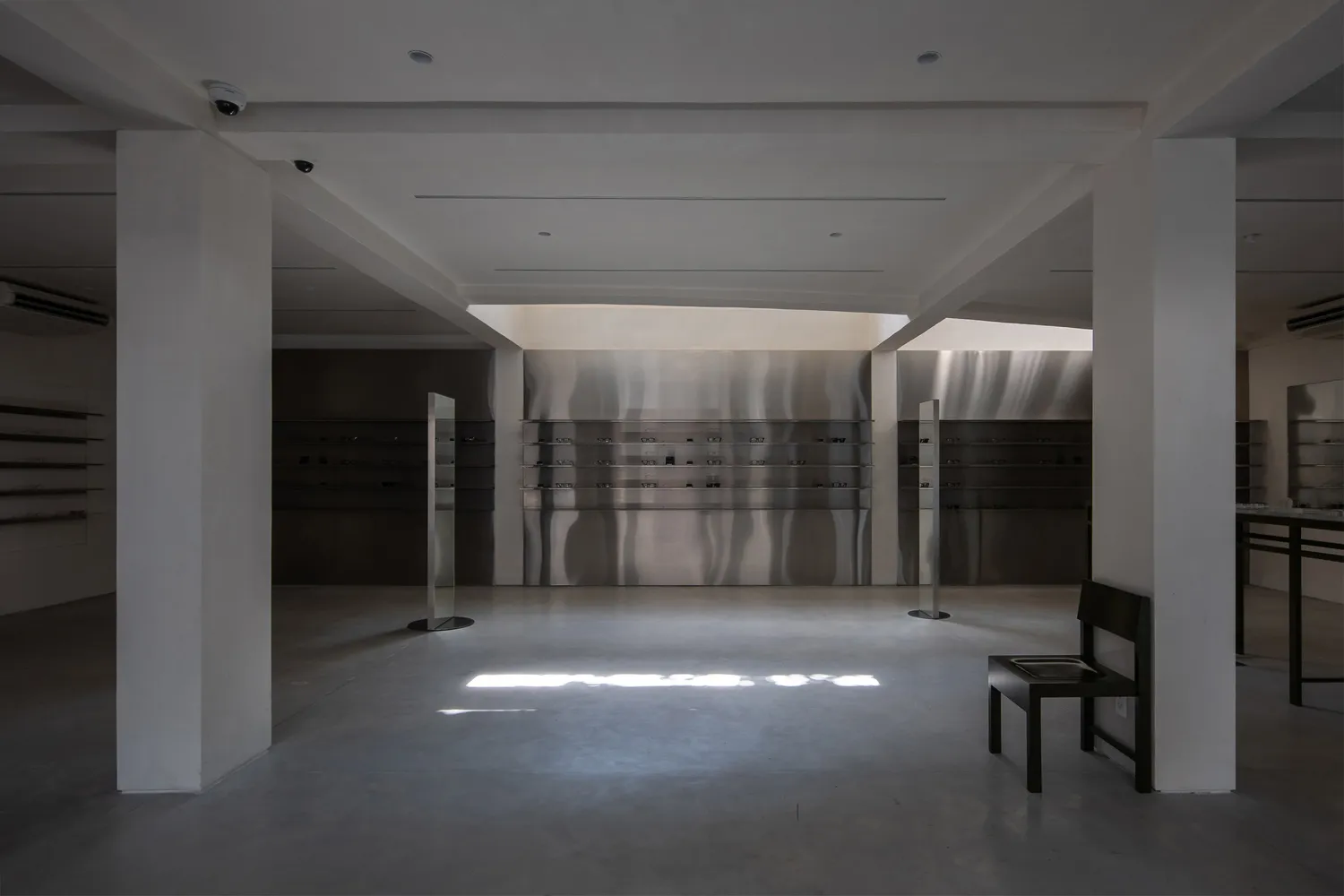 A minimalist storefront featuring concrete and glass materials, illuminated by natural light.
