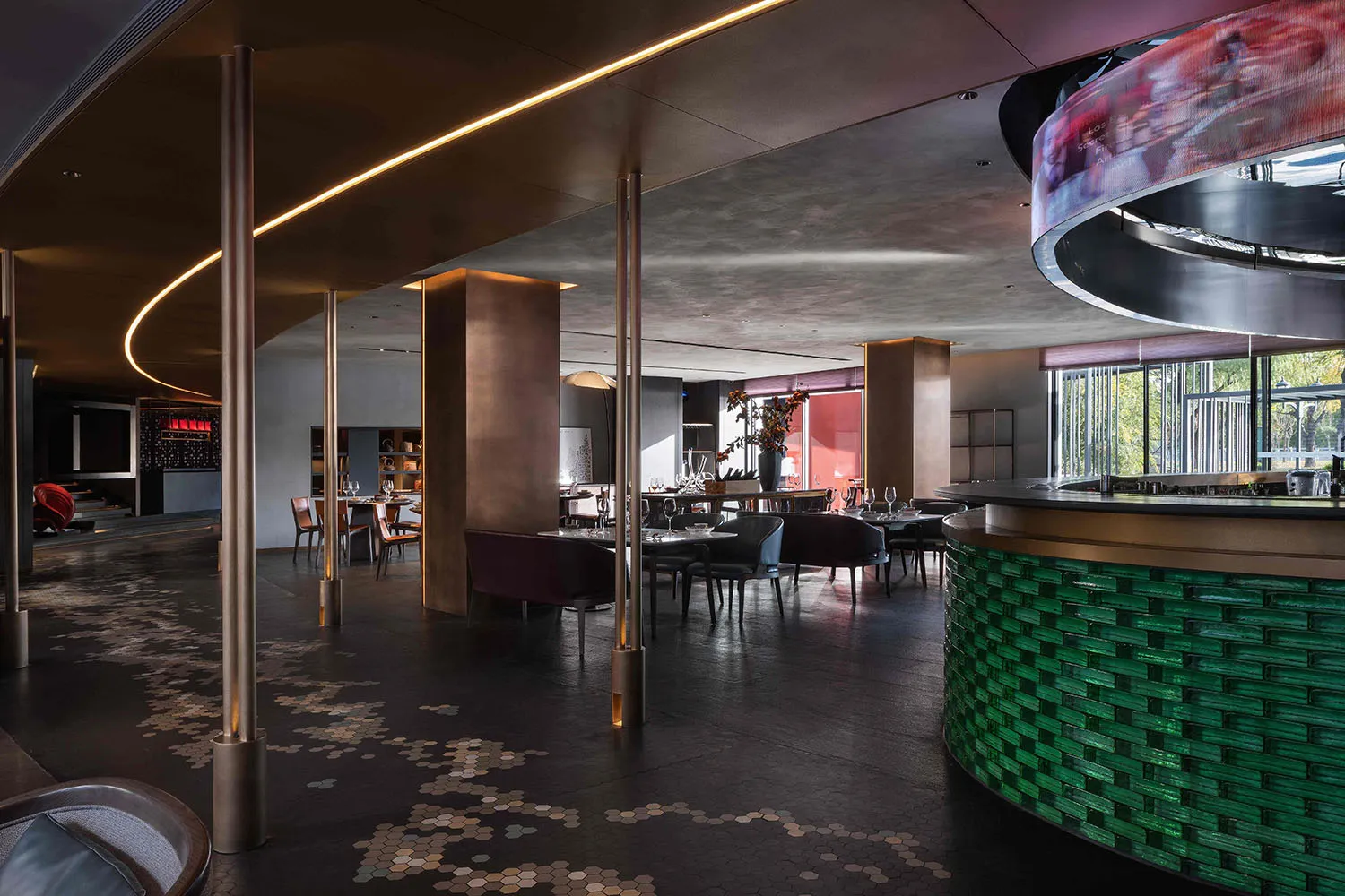 Contemporary restaurant bar interior with metallic columns, concrete walls, and brick seating.