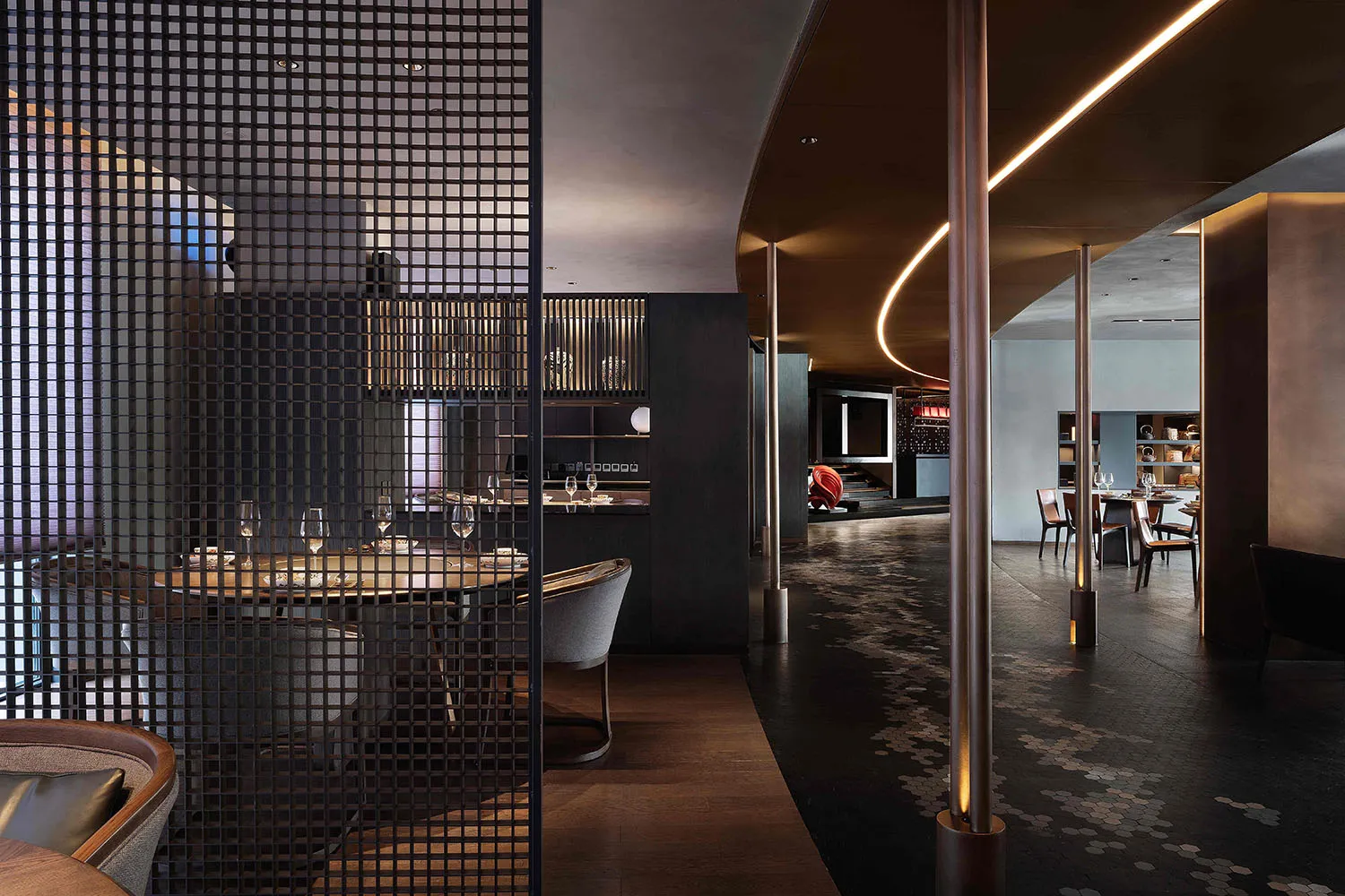 Modern restaurant interior featuring black metal mesh partitions and contemporary design.