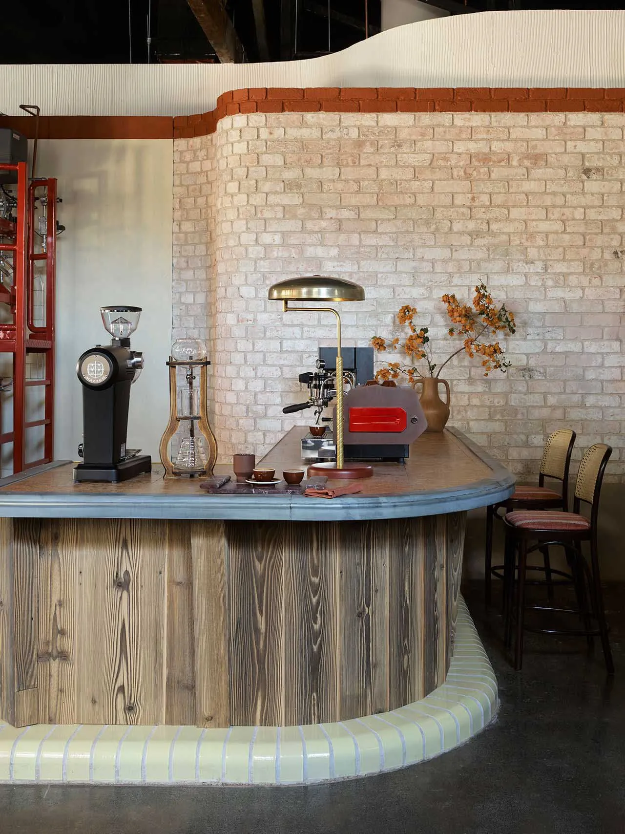 A cozy coffee shop with wooden, concrete, and brick interior elements, featuring coffee-making equipment and seating arrangem