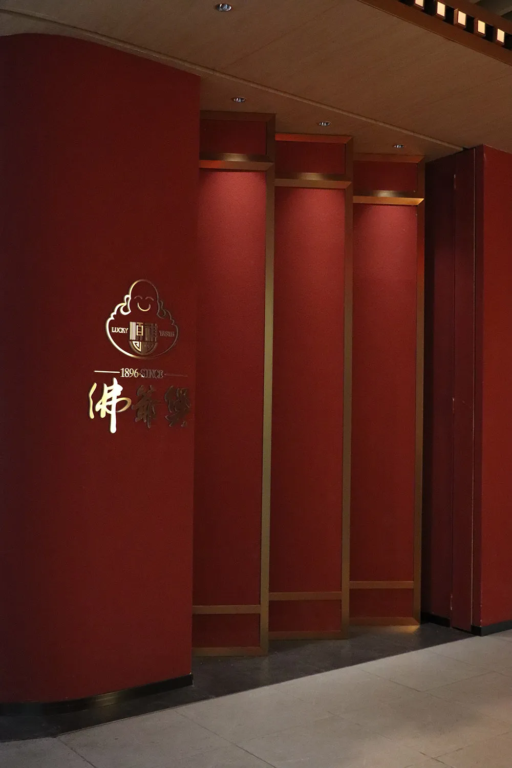 Red wall panels with illuminated logo in a restaurant setting.