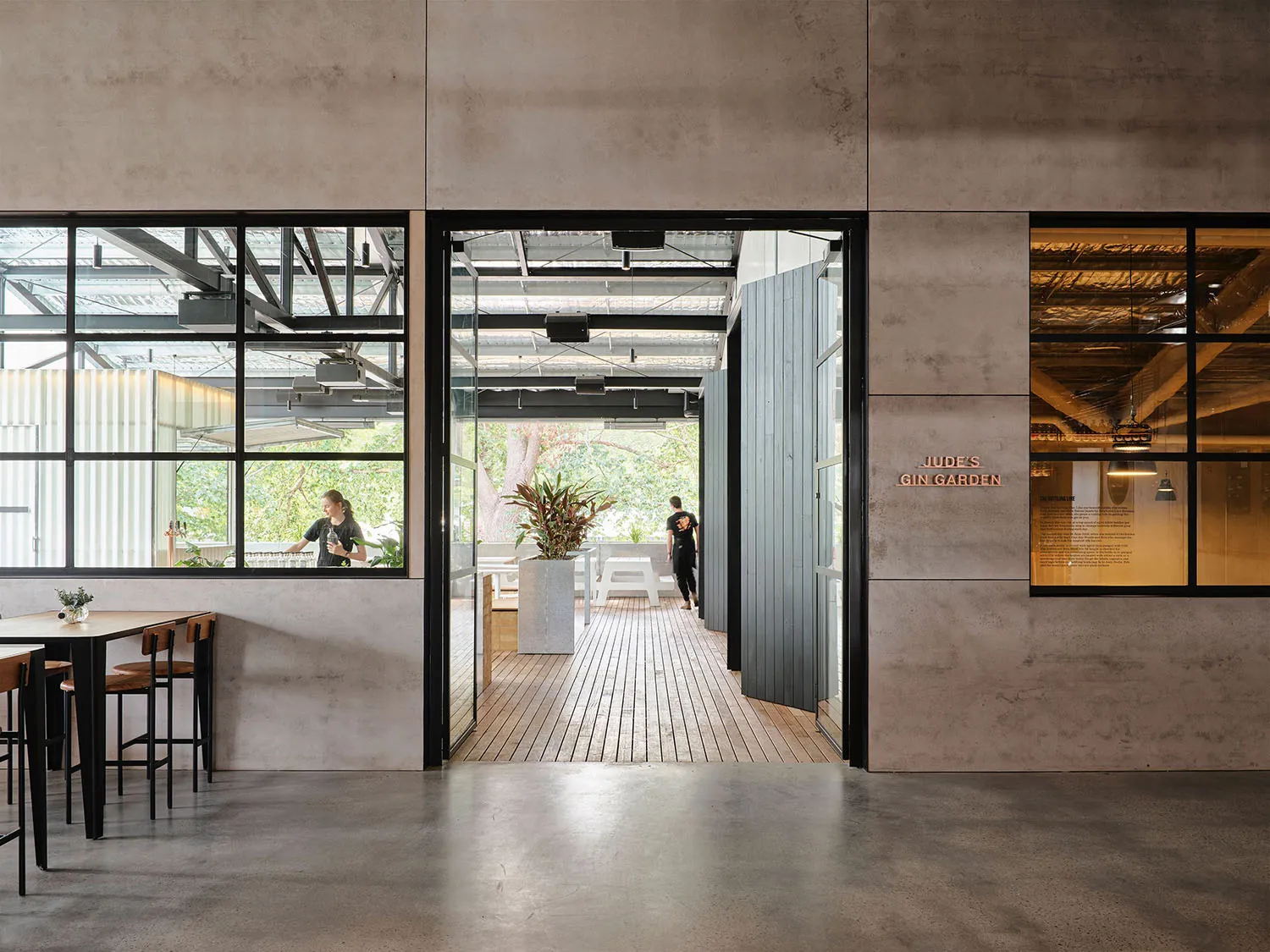 A modern cafe interior with concrete flooring and wooden seating.