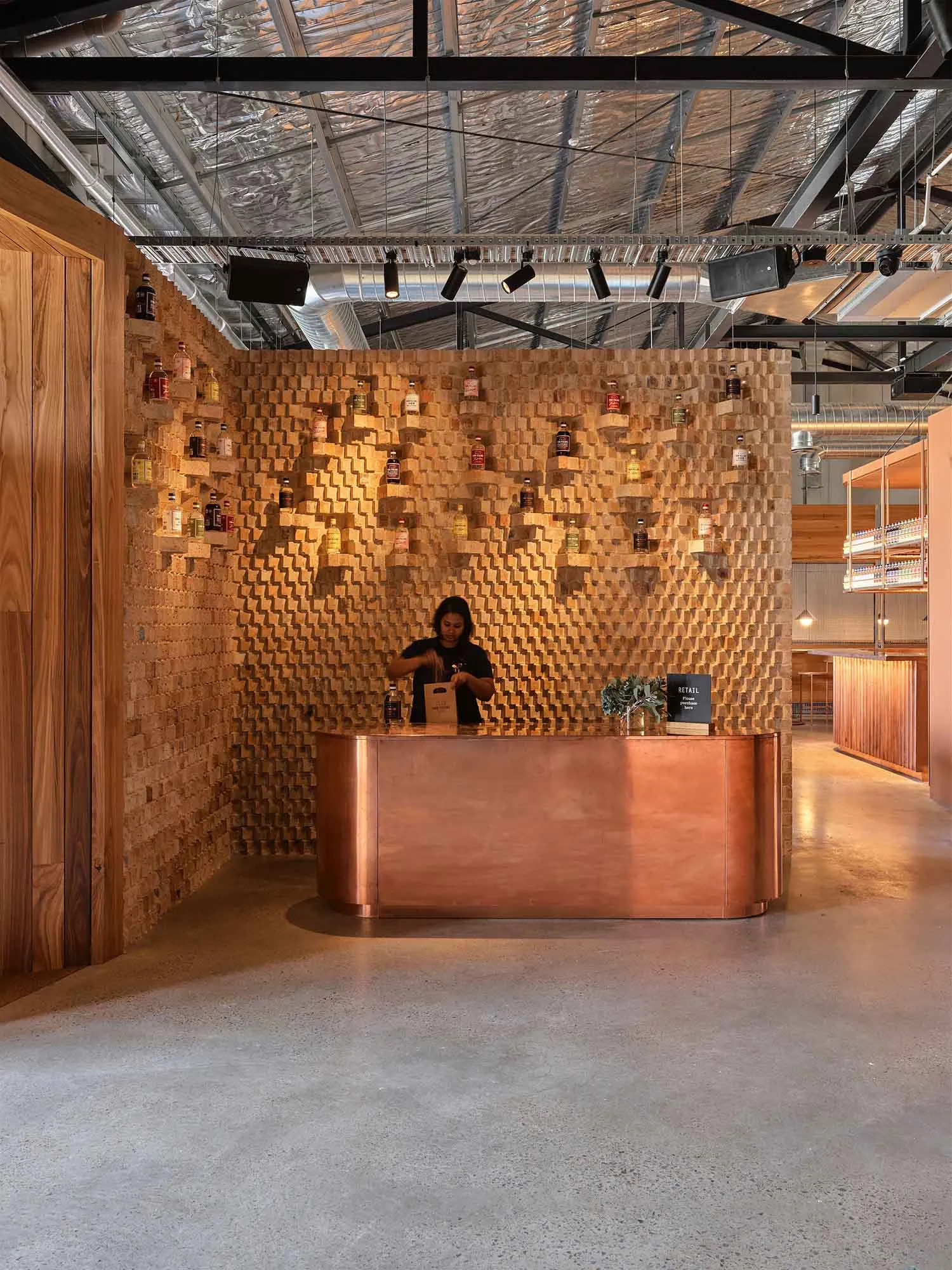 A modern retail counter made of wood with a geometric pattern wall behind it.