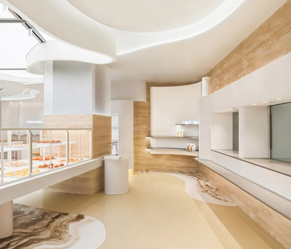 A minimalist bakery interior featuring white marble and travertine surfaces.