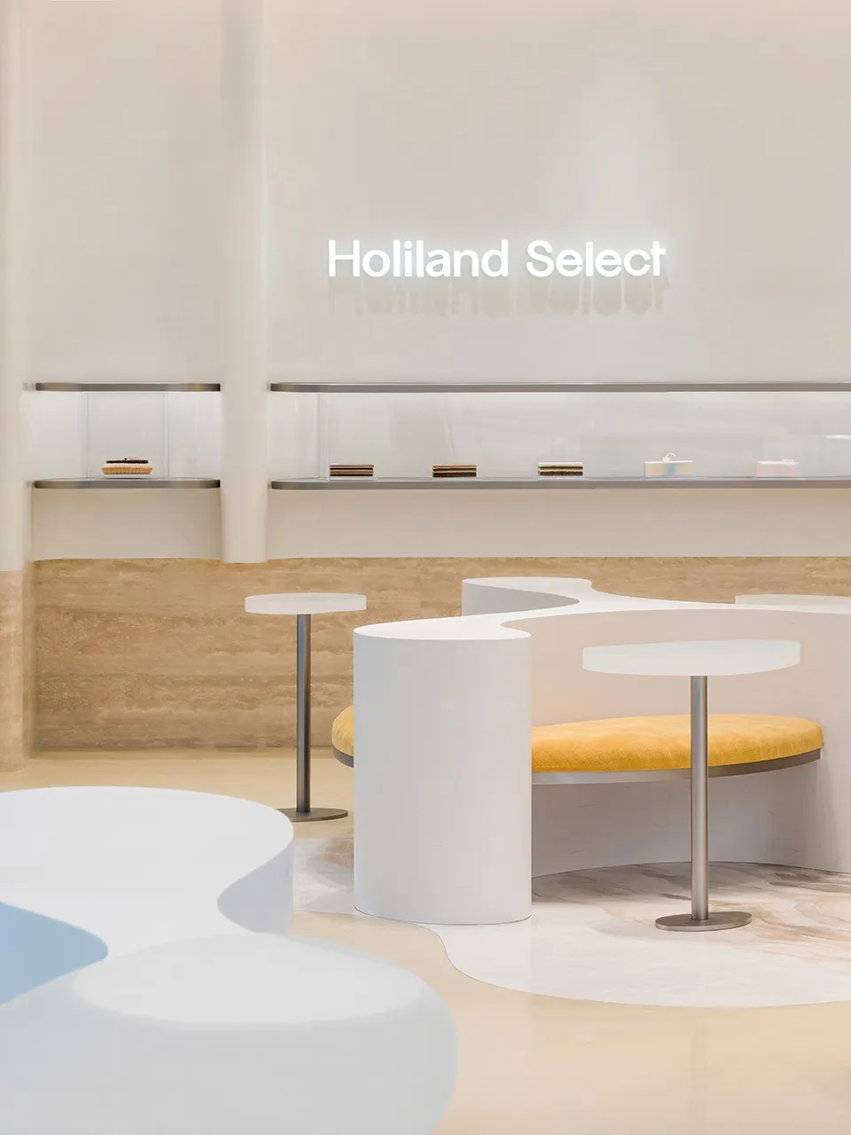 Modern minimalist coffee shop interior with white concrete elements and a yellow seating area.