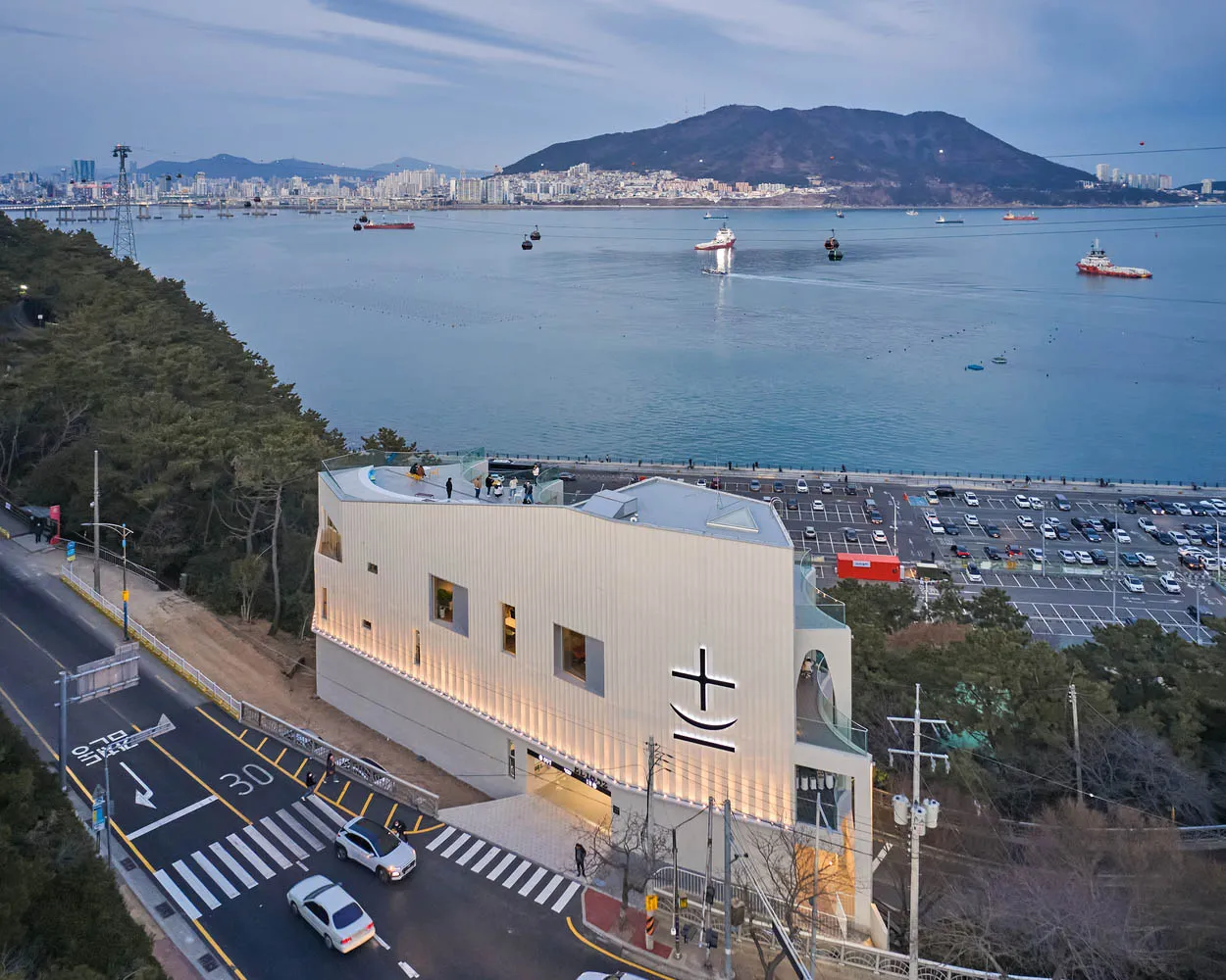 Modern building exterior featuring glass panels with a cityscape and ocean view.