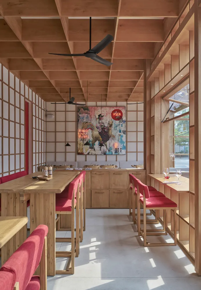 Modern restaurant interior with wooden furniture and vibrant artwork.