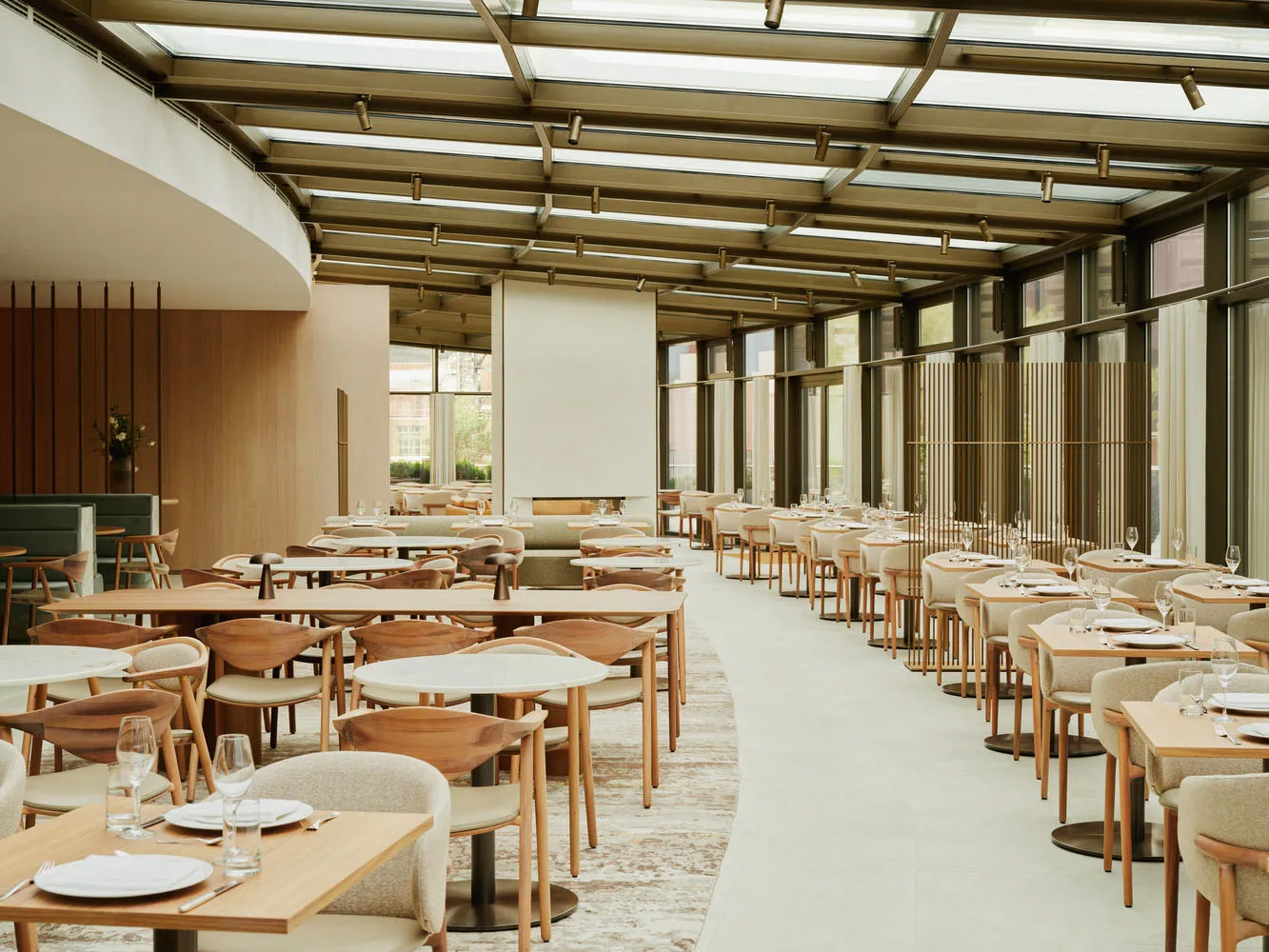 現代餐廳室內,配有木製餐桌、餐椅及玻璃隔板,營造寬敞通透的氛圍。