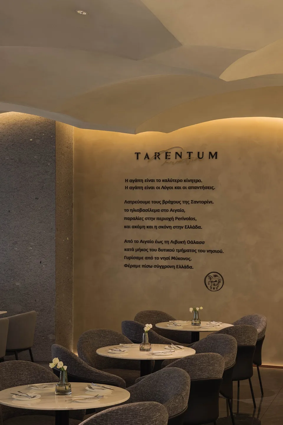 A cozy restaurant interior with textured walls and round tables set with white tableware.
