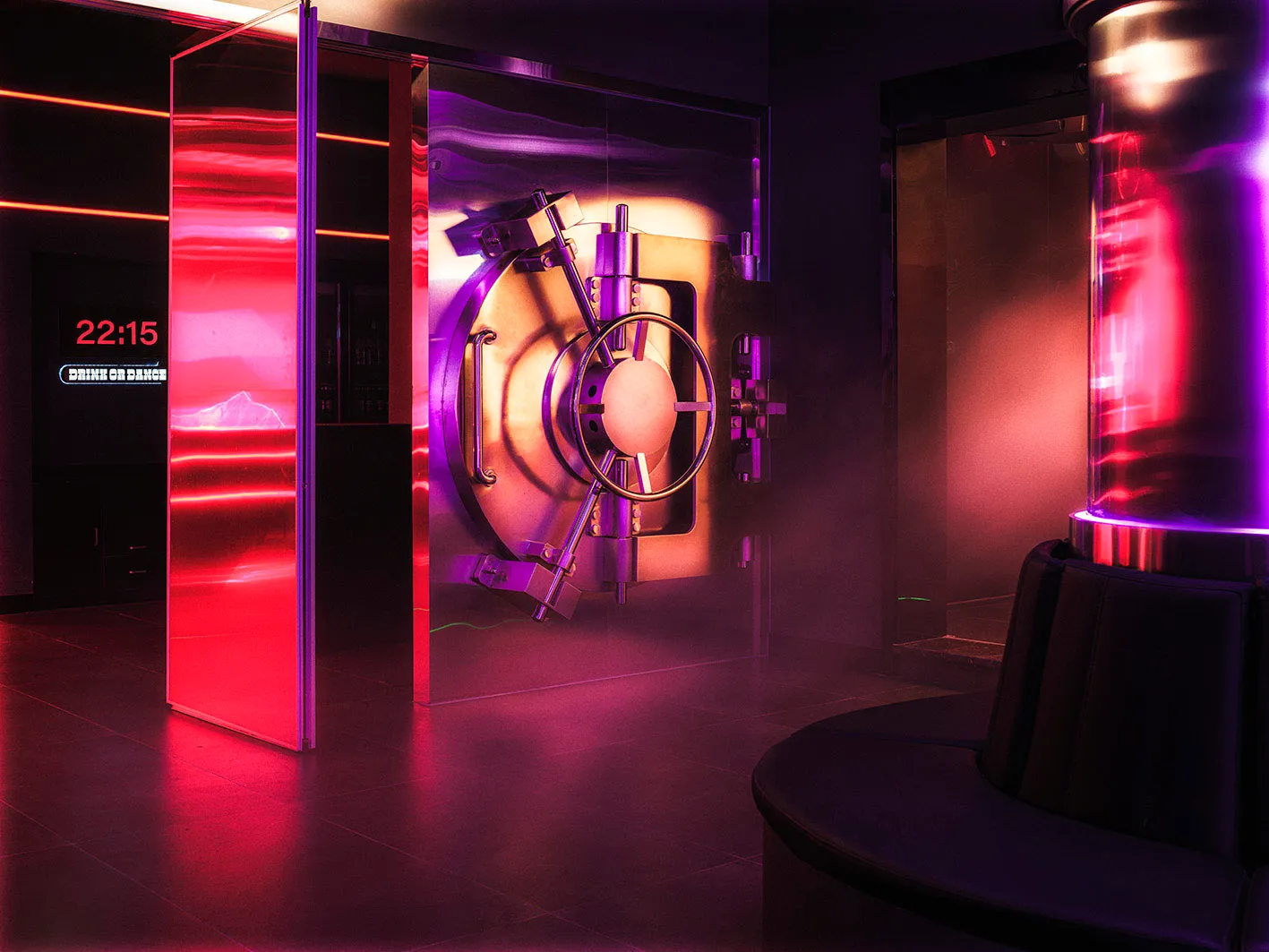 A large, illuminated metal door in a darkened bank lobby.