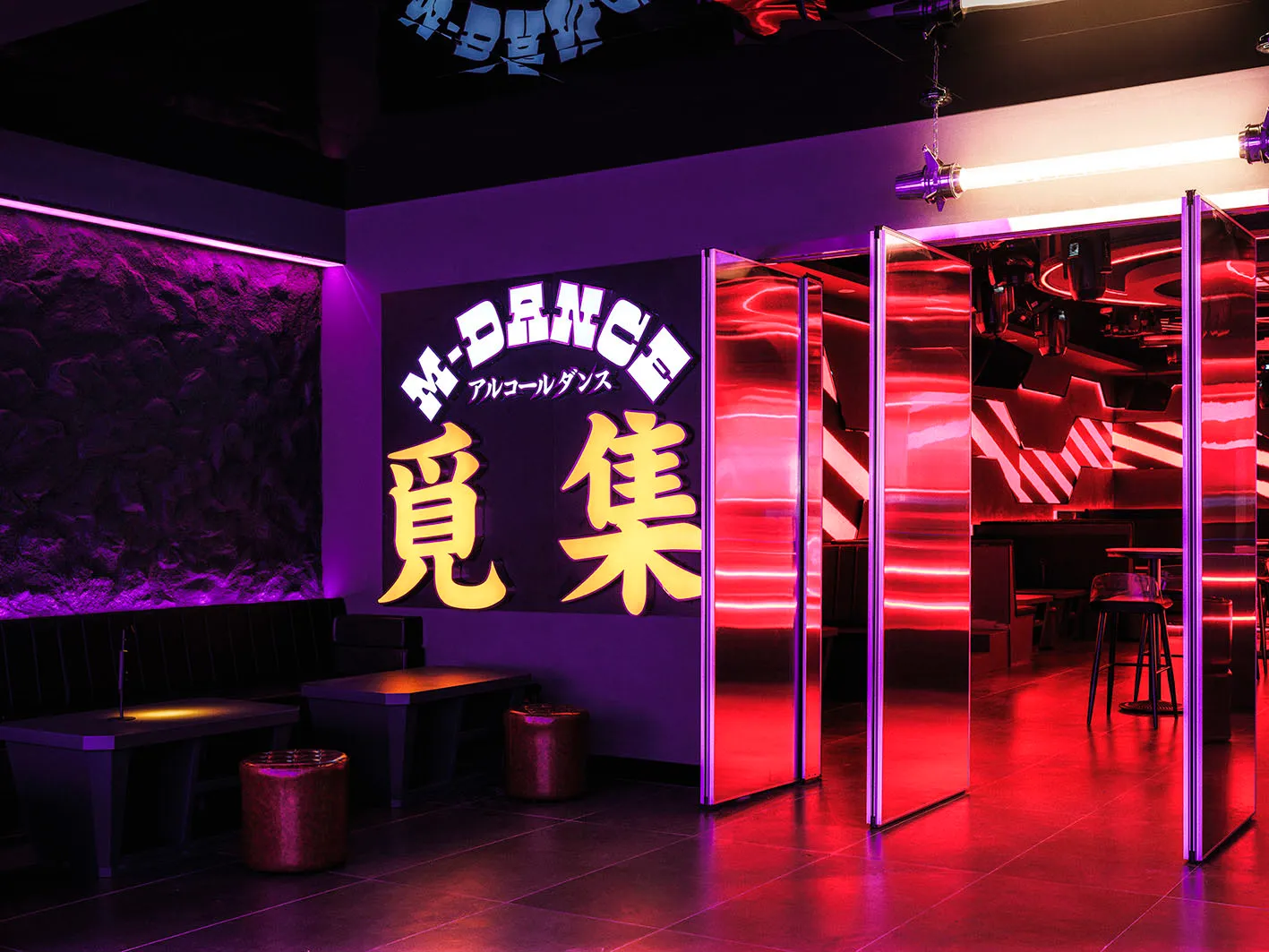 Industrial-style nightclub interior with metallic glass panels and neon lighting.