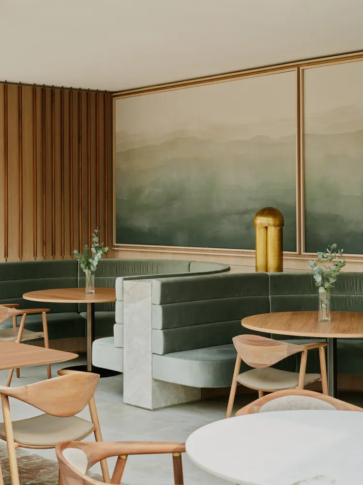 A modern cafe with green velvet seating and marble accents.