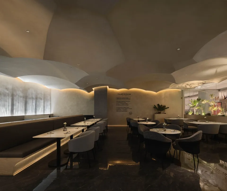 Interior of a modern restaurant featuring concrete walls, marble surfaces, and ambient lighting.