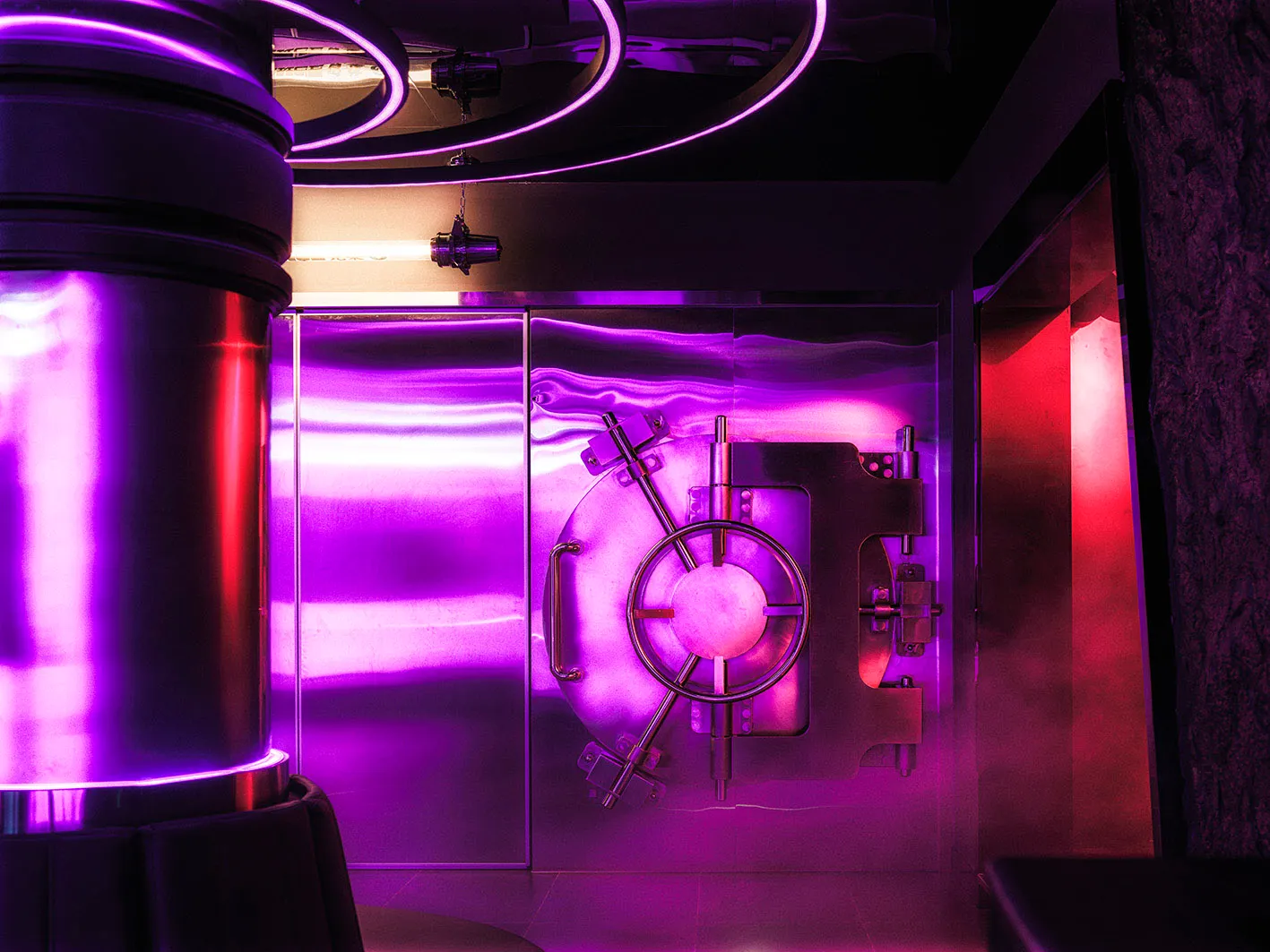 Metal lobby with purple illumination and a vault door