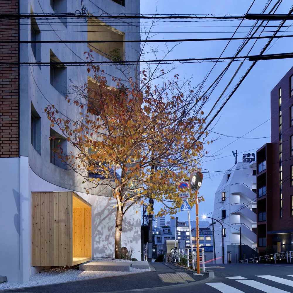 A modern urban landscape featuring a tree with autumn leaves, a residential building, and urban infrastructure.
