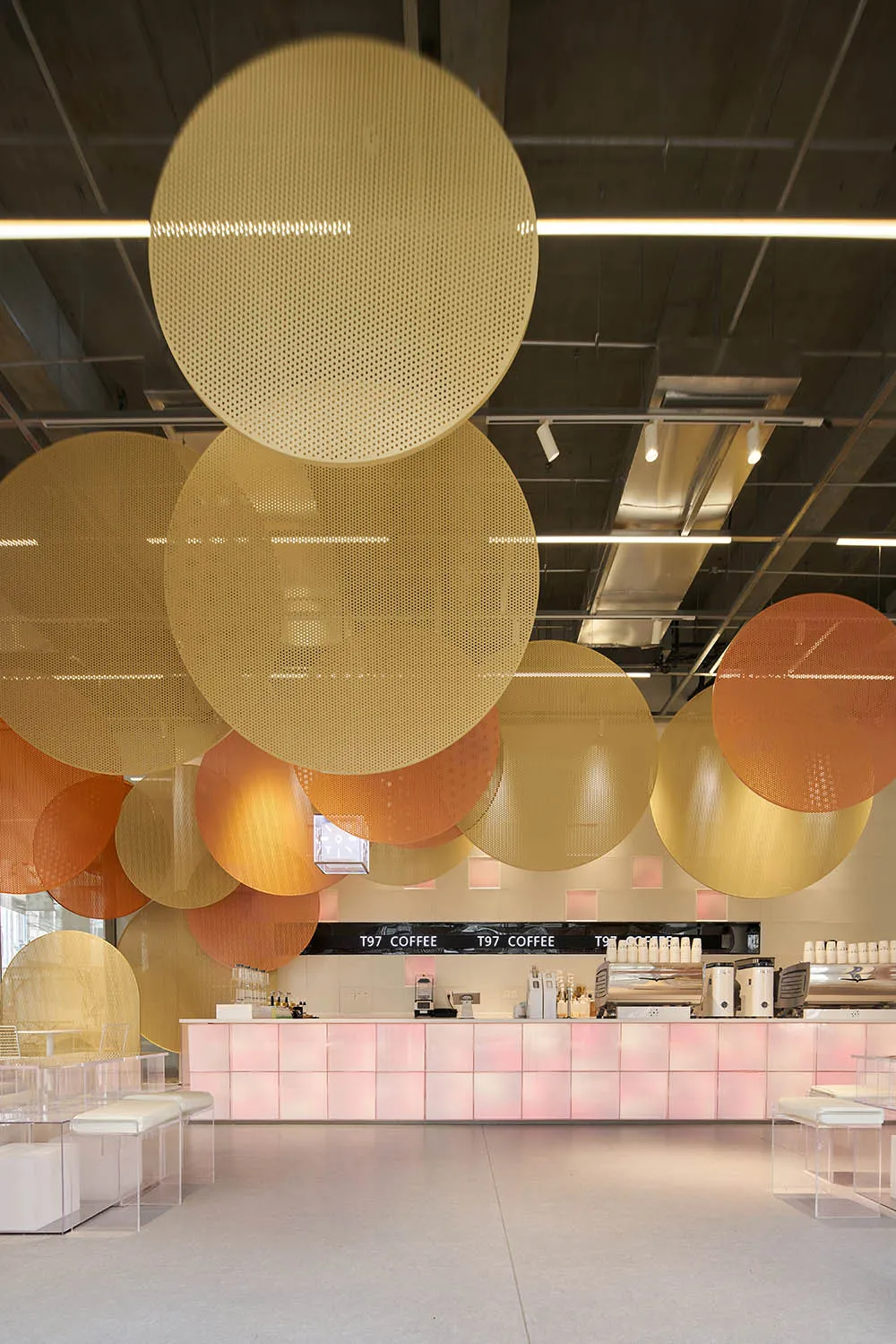 A modern coffee shop with large, circular glass pieces hanging from the ceiling.