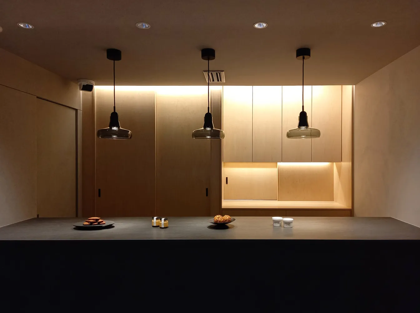 A modern kitchen with wooden cabinets and pendant lights hanging from the ceiling.