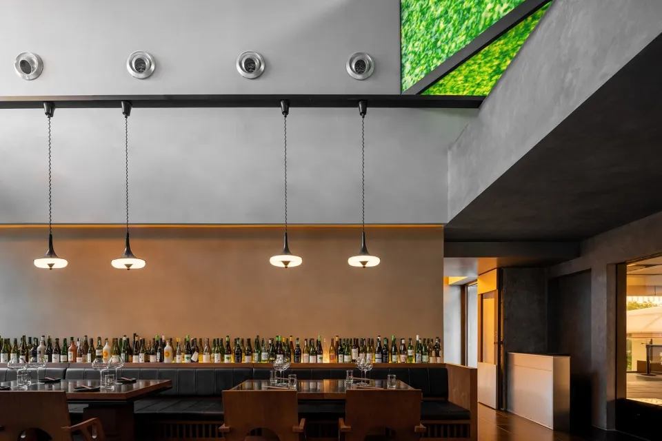 A modern restaurant bar featuring concrete walls and hanging lights.