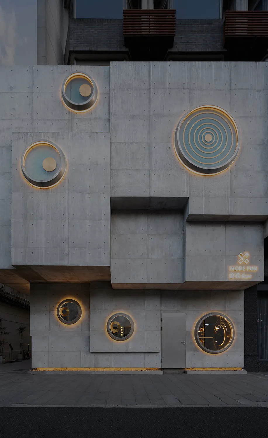 現代混凝土建築立面，圓形窗戶散發溫暖燈光。
