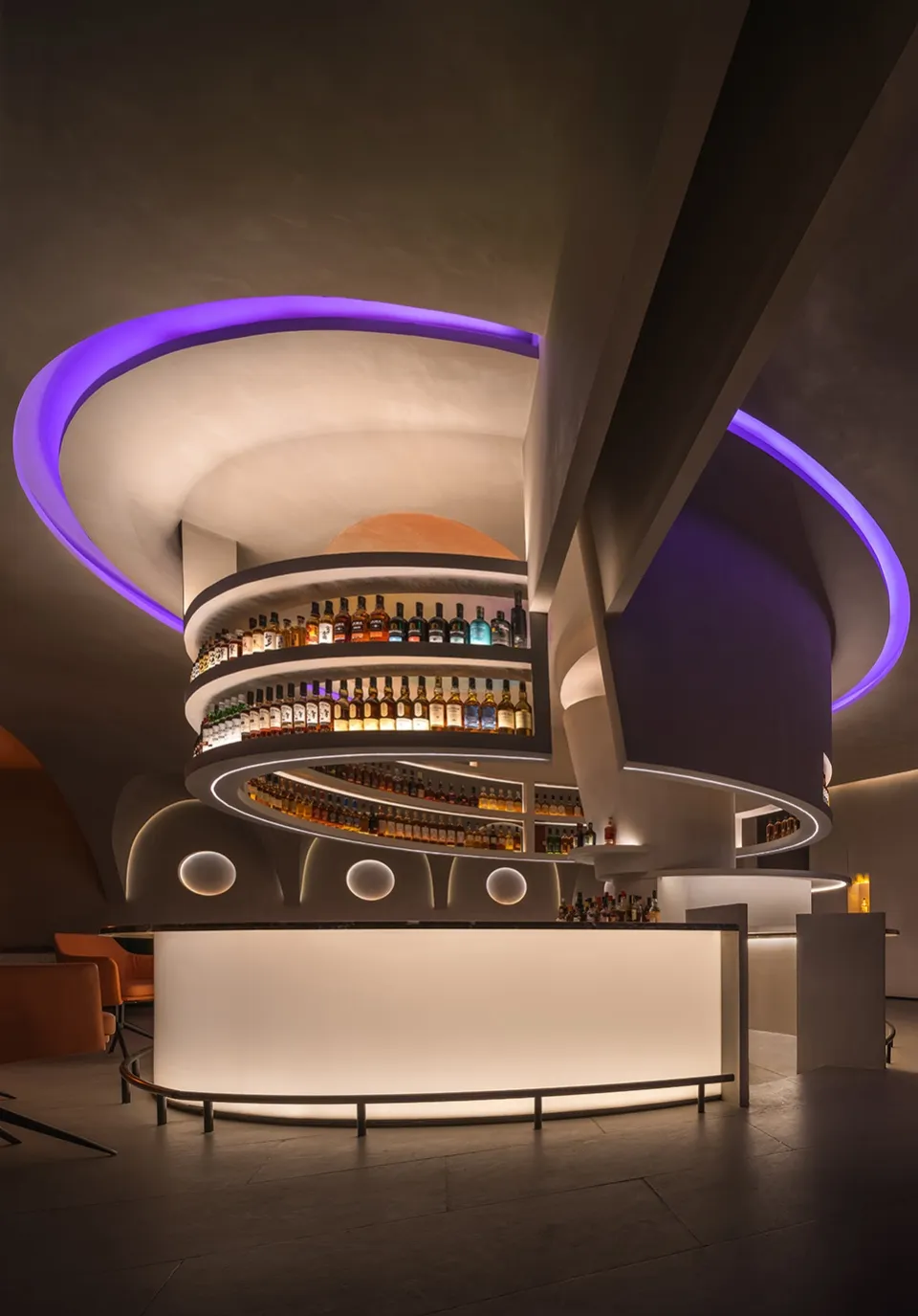 現代酒吧搭配當代燈光,設有弧形木質吧台與燈光照亮的陳列架,展示各式酒瓶