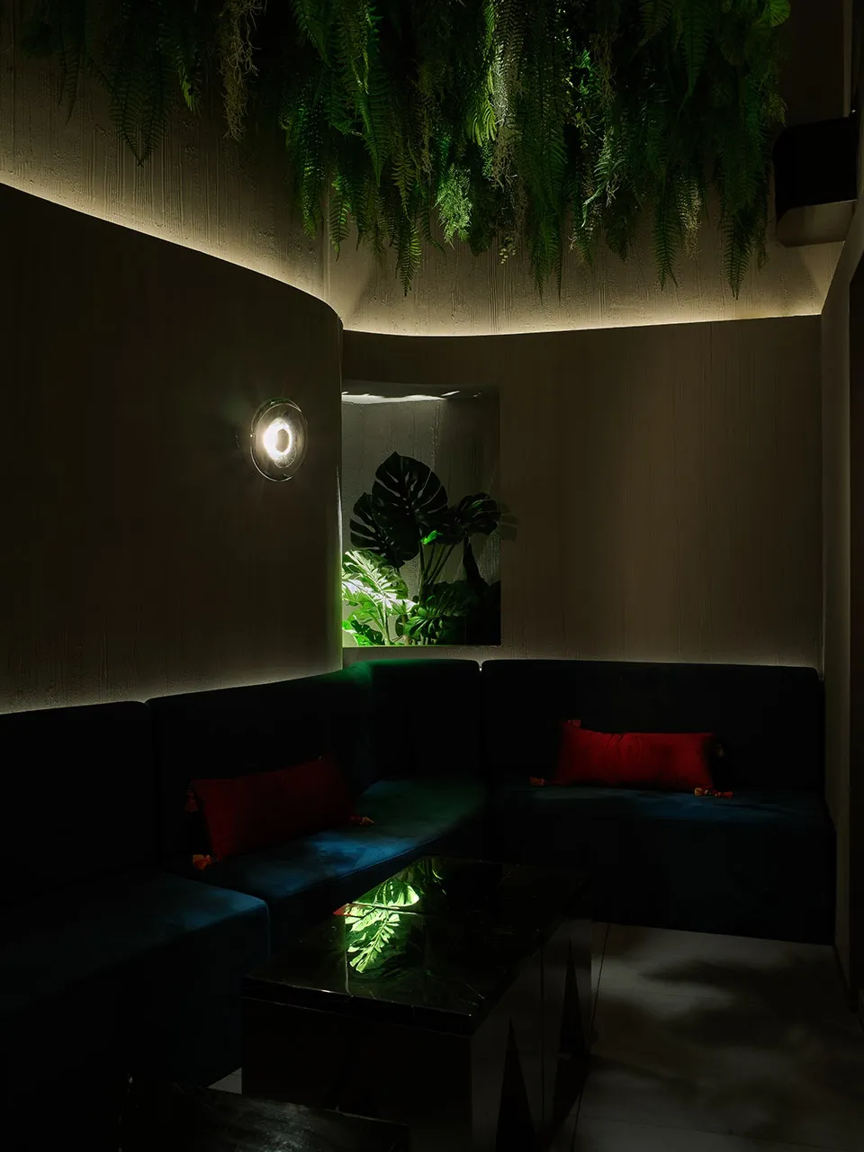 Modern cafe interior with plush seating, warm lighting, and green plants.