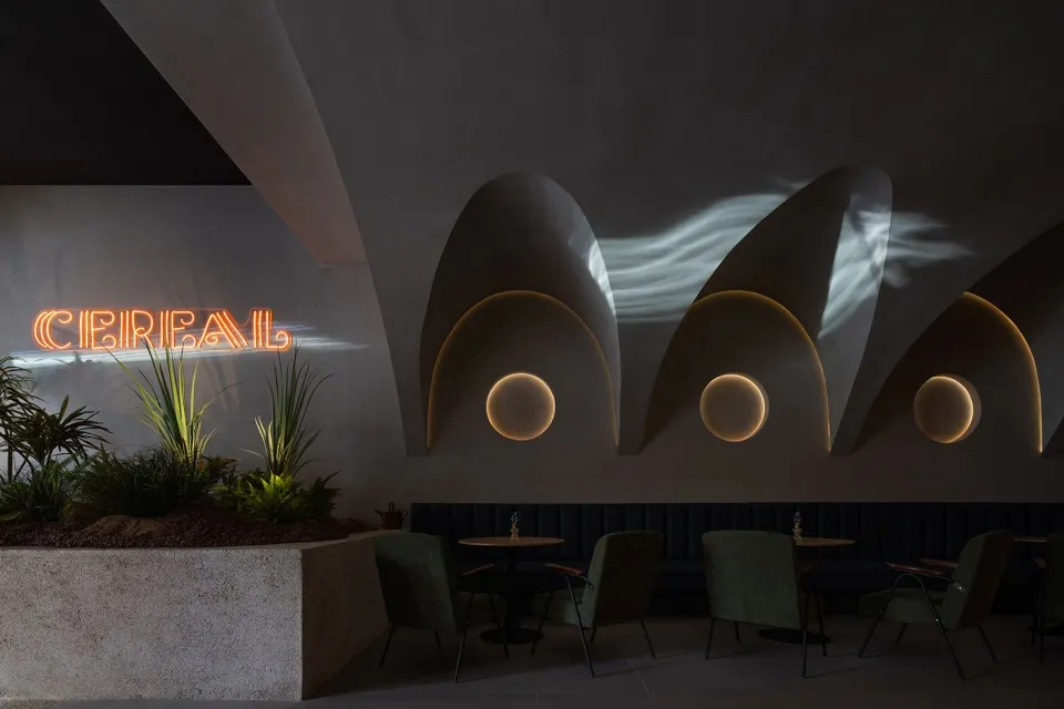 Interior design of a modern coffee shop featuring concrete walls and minimalist seating arrangements.