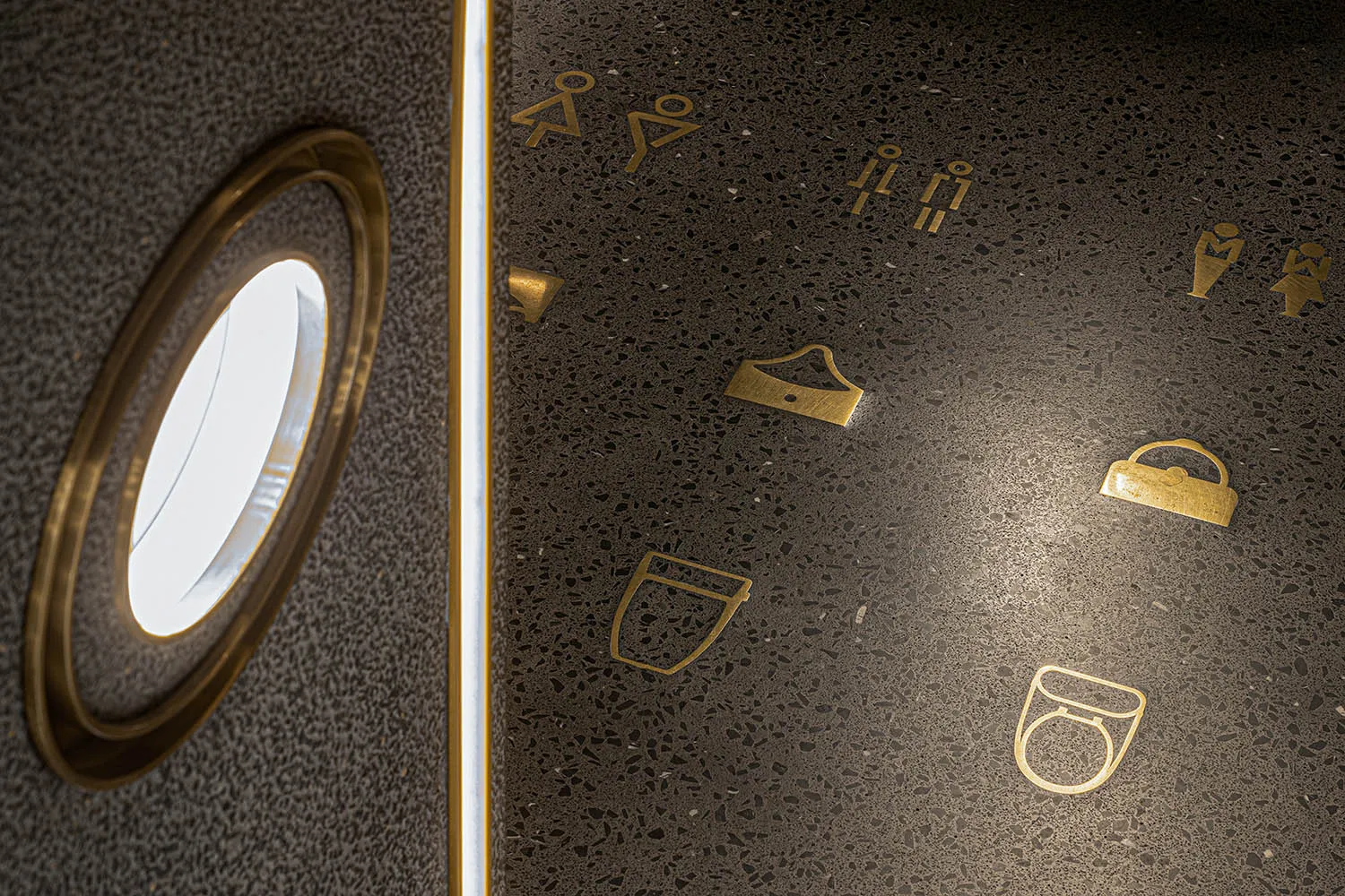 Modern public space with terrazzo tile flooring, featuring symbol icons for restrooms and other amenities.