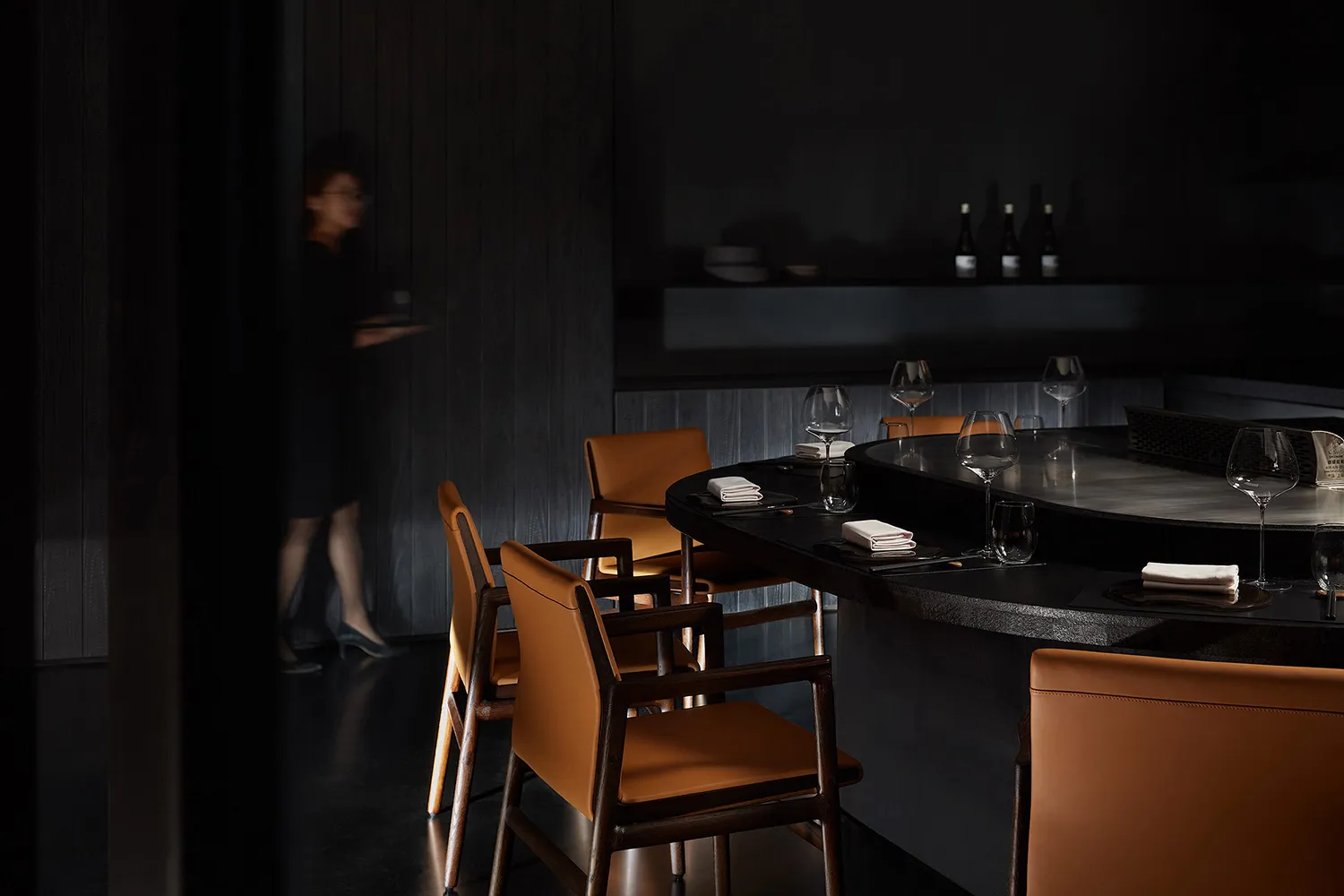 A stylish modern restaurant interior with dark wood and leather accents.