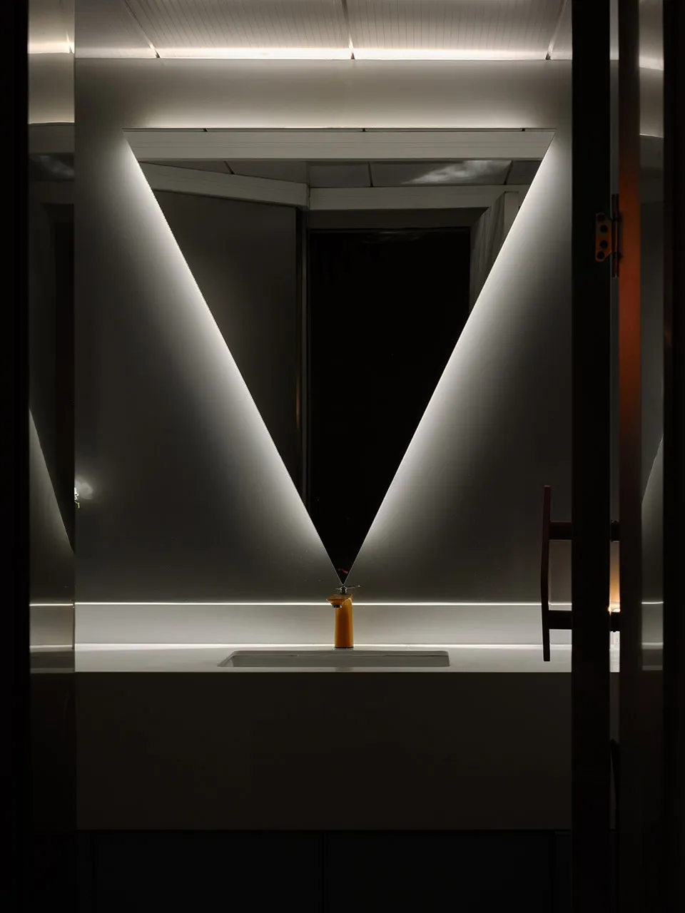 A modern bathroom with a transparent triangle-shaped design, featuring glass walls and a minimalist aesthetic.