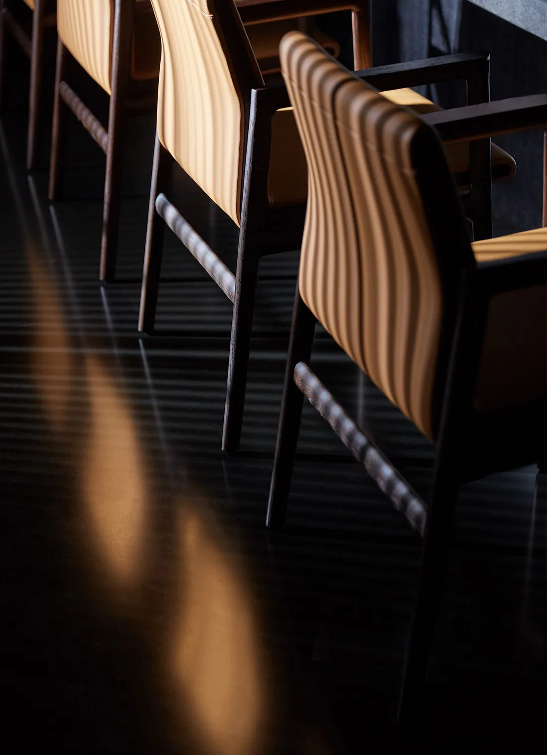 Rows of orange bar stools on a sleek black concrete floor