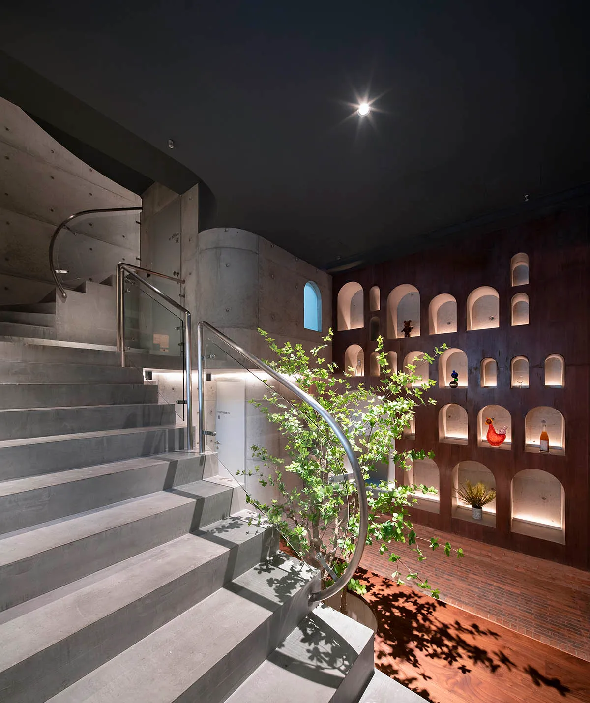 Industrial-style concrete staircase with glass railings and a plant