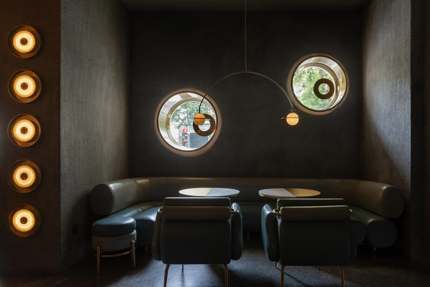 A minimalist coffee shop interior featuring leather seating, concrete walls, and wooden accents.