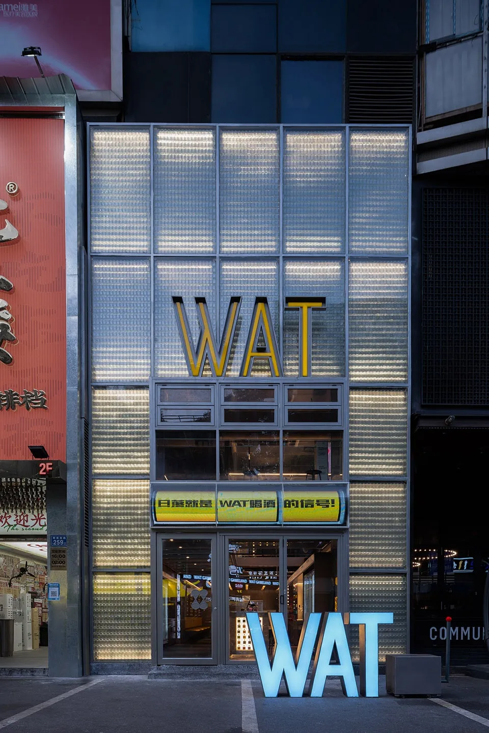 A modern storefront with large glass windows displaying illuminated signage
