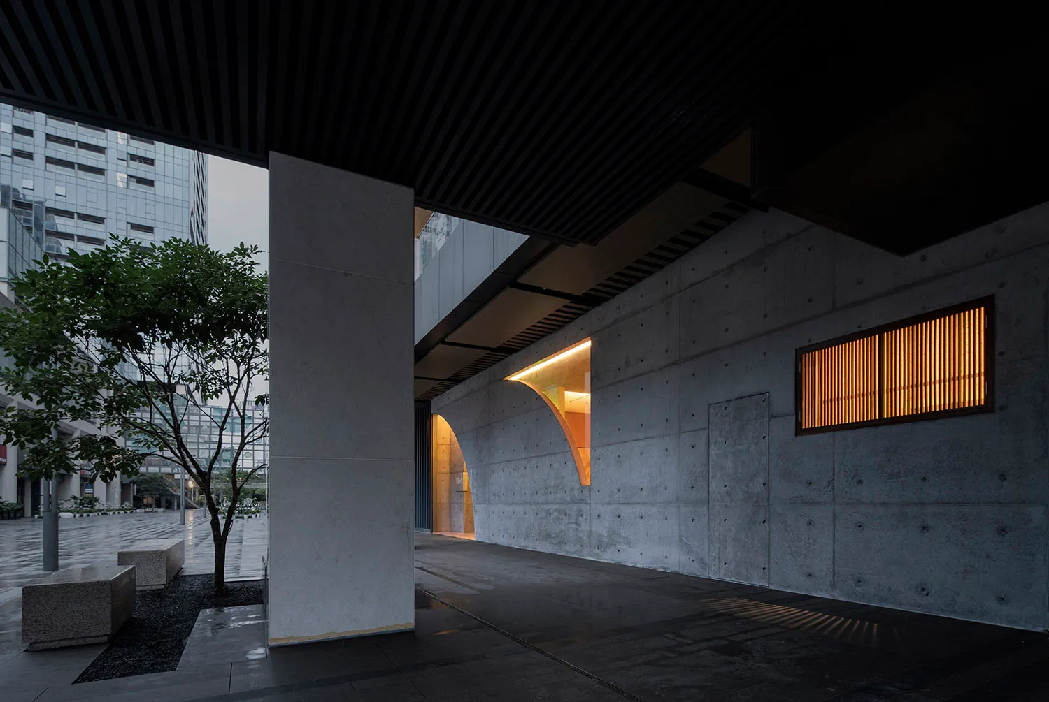 A modern interior space featuring concrete walls and a ceiling with illuminated lighting.