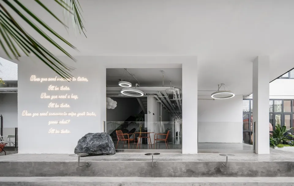 Modern restaurant with concrete tables and chairs, minimalist design, and neon lighting