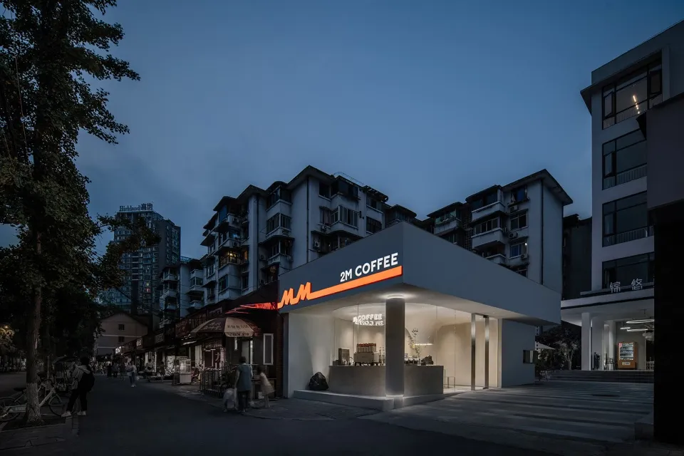 夜間視角的現代街景咖啡廳，採用混凝土材質並搭配發光招牌。