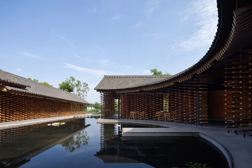 Modern architectural design featuring wooden structures and a reflective water feature in a public space.