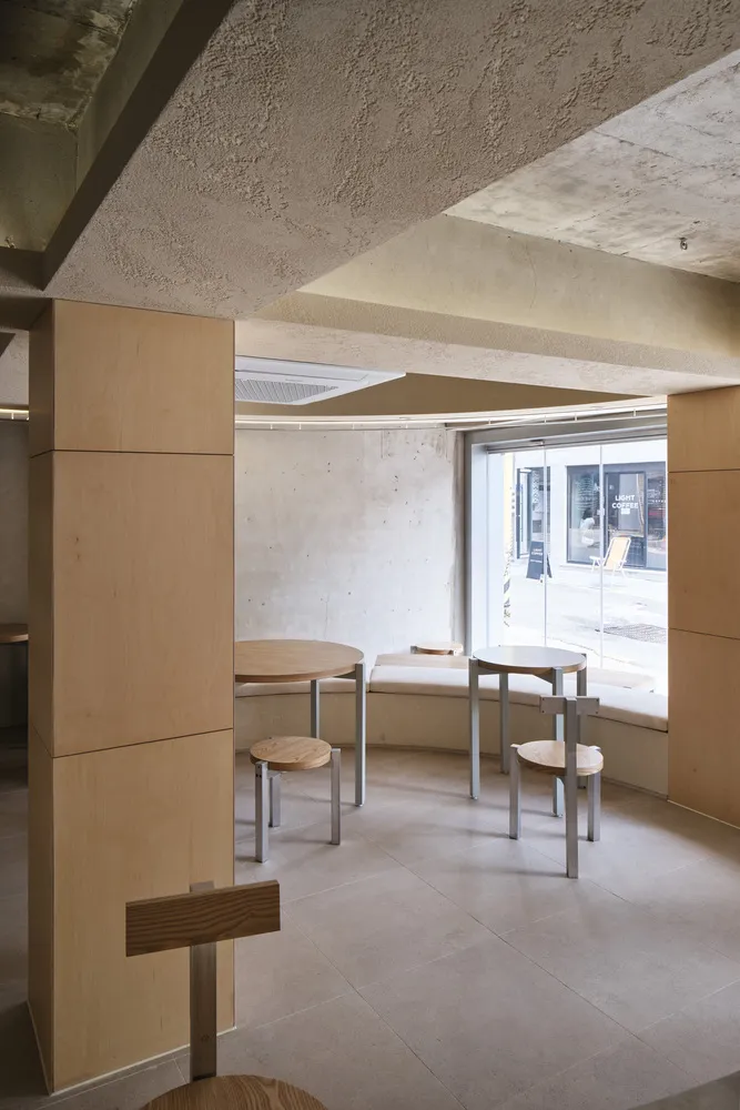 Cafe interior with minimalist design featuring concrete walls and wooden furniture.