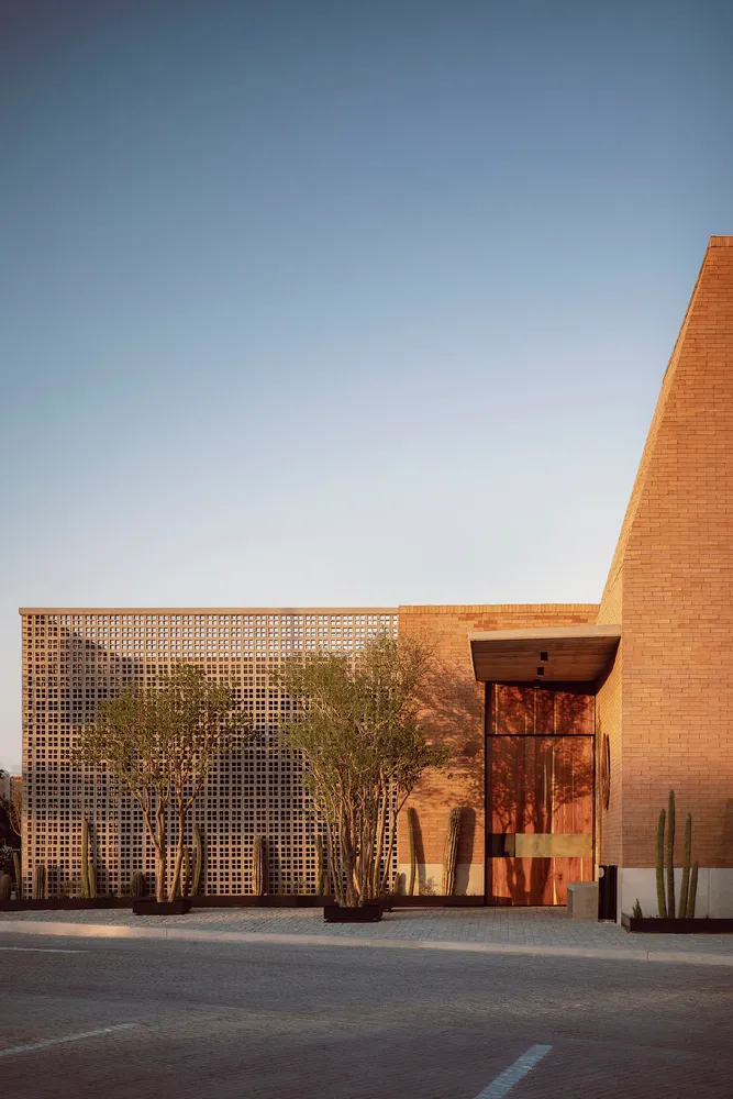 A modern building with a brick exterior, featuring large windows and a geometric design.