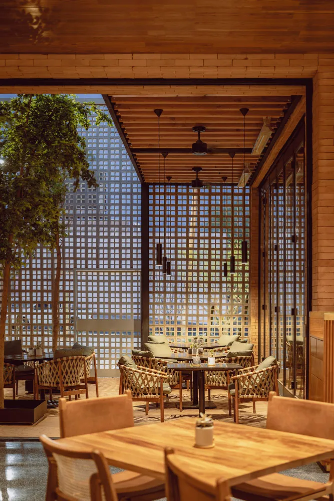 Indoor restaurant space featuring woven furniture with a wood frame and wooden ceiling beams.