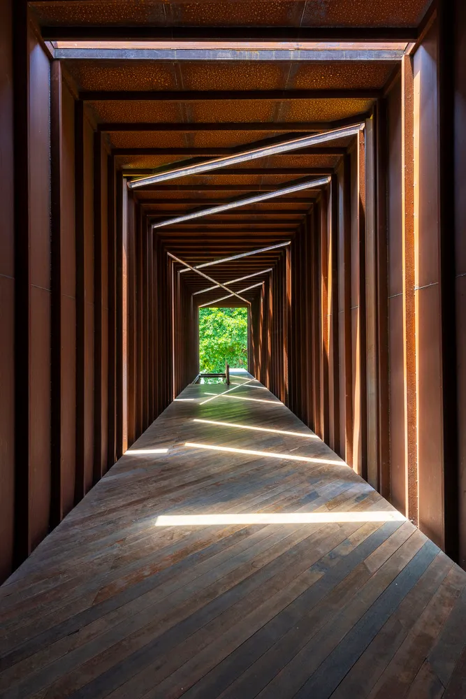 A modern corridor with a wooden floor and walls extending into the distance.
