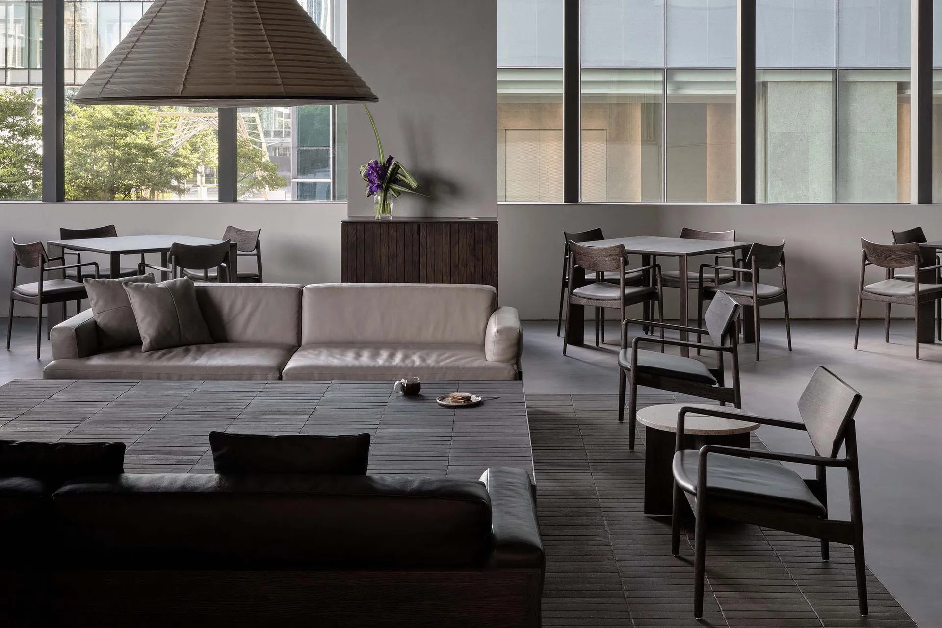 Modern coffee shop interior with comfortable seating and wooden furniture, featuring a large window and contemporary design.